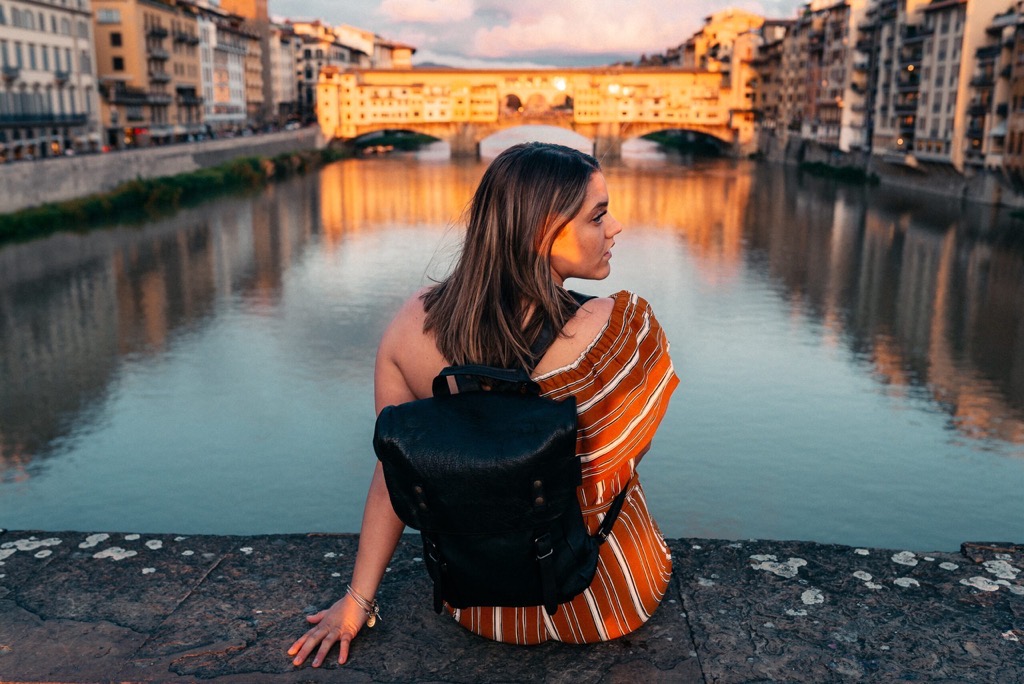 Woman overlooking the Arno River and Ponte Vecchio in Florence at sunset