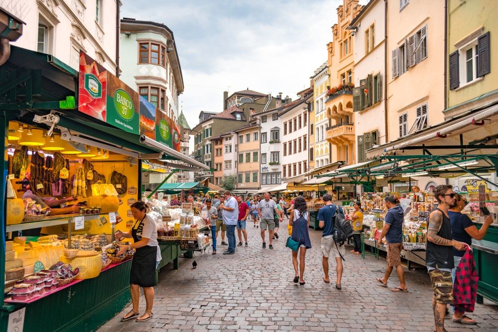 Mercado al aire libre en una calle empedrada de Italia con puestos de queso y embutidos