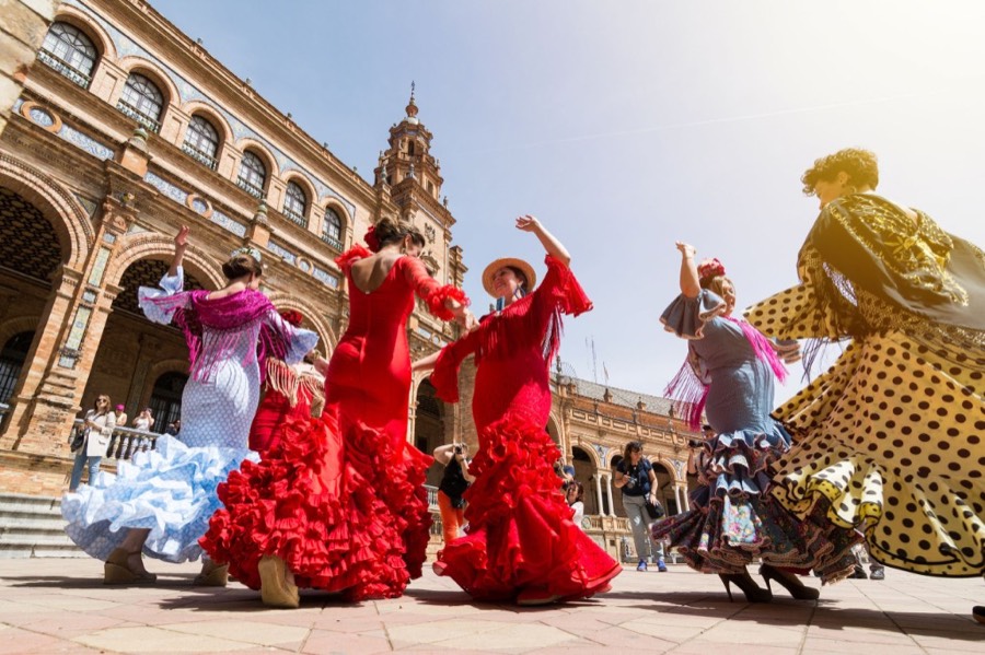 Flamenco dancers in colorful dresses at Plaza de España in Seville